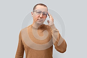 Tired man suffering from headache on gray background.