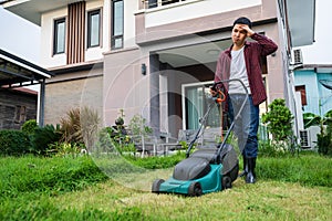 Tired man using lawn mower cutting grass at home