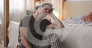 Tired man using mobile phone in bedroom