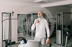 a tired man wipes sweat from his face with a towel after working out on a treadmill. cardio workout