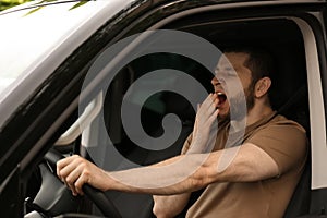 Tired man yawning while driving his car