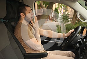 Tired man yawning while driving his car