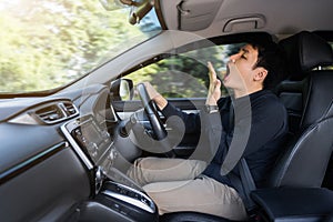 Tired man yawning and sleepy while driving car