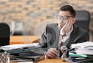 Tired mature businessman at table in office. Time management concept