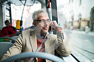 Tired mature businessman travelling by bus in city.