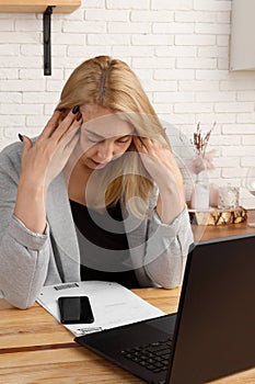 tired middle-aged business woman working in a home office, sitting at a desk with documents