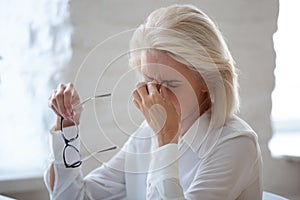 Tired middle-aged woman suffer from headache in office