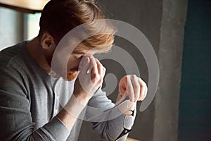 Tired millennial man massaging nose feeling fatigue from work