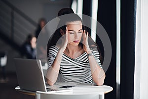 Tired minded woman thinking about way to complete a task. Beatiful female having a headache during a break in a cafe.