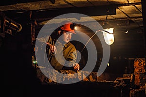 A tired miner in a coal mine looks at the light. Work in a coal mine. Portrait of a miner. Copy space.