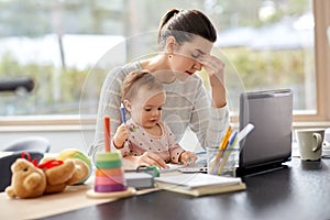 Tired mother with baby working at home office