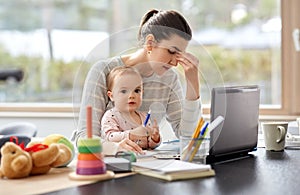 Tired mother with baby working at home office
