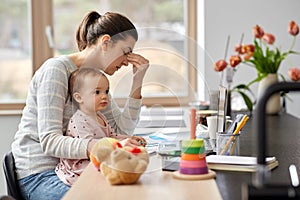 Tired mother with baby working at home office