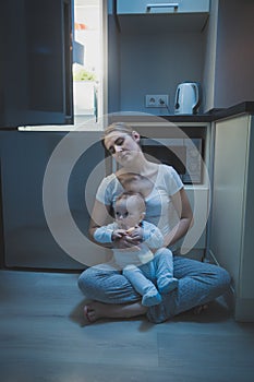 Young tired mother fell asleep while feeding her baby boy with milk at night