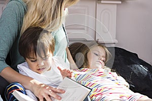 Tired mother reading book to kids