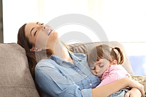 Tired mother sleeping with her baby daughter