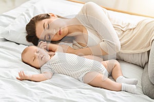 Tired mother sleeping with her newborn son, exhausted after babycare photo