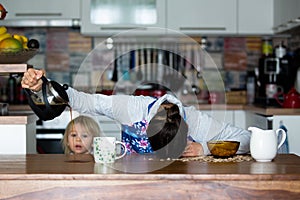 Tired mother, trying to pour coffee in the morning. Woman lying on kitchen table after sleepless night