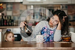 Unavený matka snaží na lít káva v ráno. žena ležící na stůl po bezesný noc 