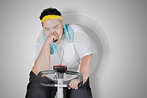 Tired obese man doing workout with exercise bike