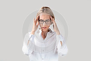 Tired office employee having terrible headache or suffering from work stress on light background
