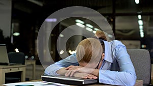 Tired office employee lying on laptop, concept of daily routine and overwork