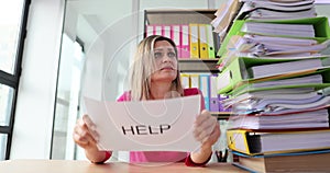 Tired office worker feels overloaded with work and holds up help notice