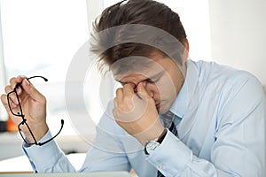 Tired office worker touching his bridge of nose to give rest to