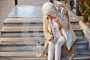 Tired old age female with headache in the city