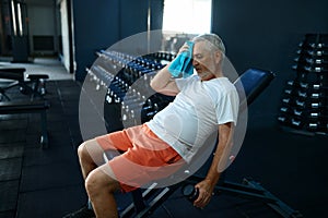 Tired old man with towel leisures after workout