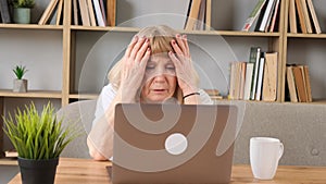 Tired old woman working with laptop at home. Work online in retirement