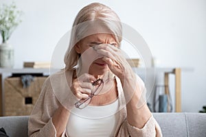 Tired older lady suffering from dry eyes syndrome. photo