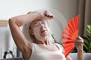 Tired overheated middle aged lady wave fan complain on heat