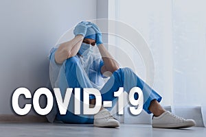 Tired overwhelmed doctor sitting on floor in hospital. Medical system collapse during coronavirus pandemic