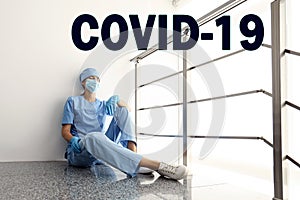 Tired overwhelmed nurse sitting on floor in hospital. Medical system collapse during coronavirus pandemic
