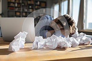 Tired overworked businessman sleeping at desk covered crumpled papers