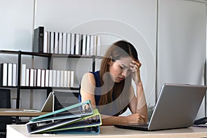 Tired overworked young Asian business woman suffering from severe depression in office