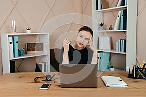 Tired  overworking businesswoman at workplace in office, holding her head in hands and thinking about successful financial strateg