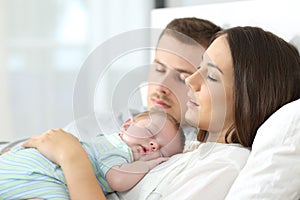 Tired parents sleeping with their baby photo