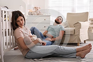 Tired parents with their baby sleeping on floor in children`s room