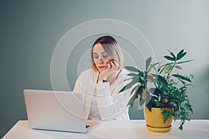Tired pensive Caucasian business woman working on laptop computer. Freelancer working remotely on Internet from home office.