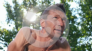 Tired perspiring man standing in plank position in sunbeam outdoors working out. Bottom view of Caucasian sweating