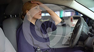 Tired policewoman taking off service cap sitting in patrol car, night shift