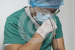 Tired praying doctor at the hospital. A doctor, a nurse who is thinking about treating a disease and a pandemic. Surgeon after