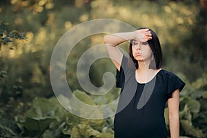 Tired Pregnant Woman Taking a Walk in Nature on Hot Day