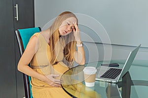 Tired pregnant woman at work drinks coffee caution advised due to potential harm of caffeine during pregnancy