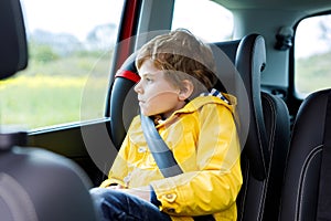 Tired preschool kid boy sitting in car during traffic jam