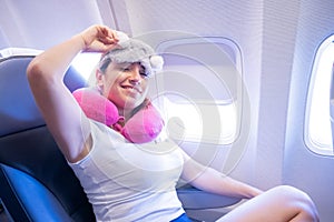 Tired red-haired woman sleeping on the plane with an eye mask and a neck pillow