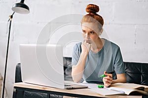 Tired redhead young woman is highlighting important things in paper documents.