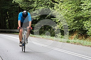 Tired road cyclist going solo uphill with copyspace